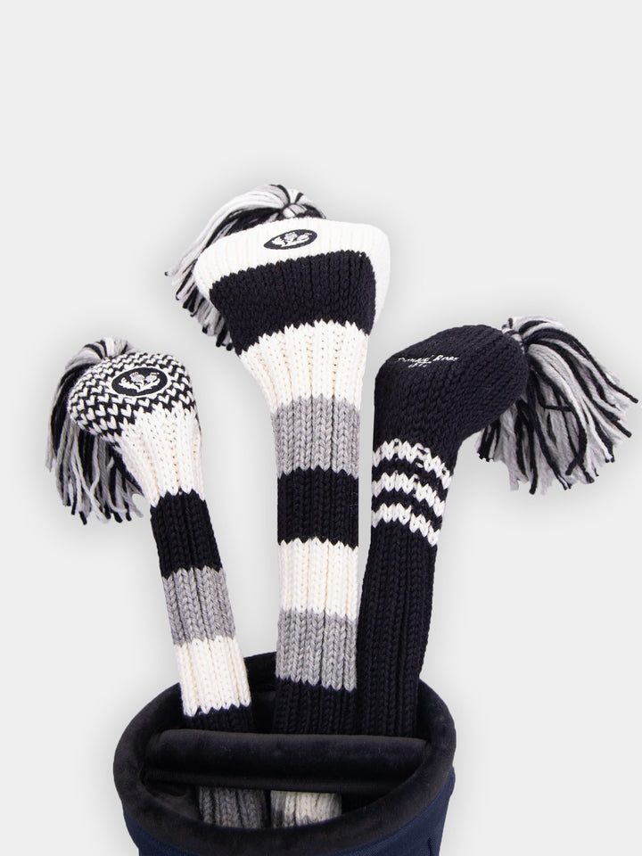 Three black, white, and gray striped knit golf club headcovers with tassels are displayed vertically in a golf bag