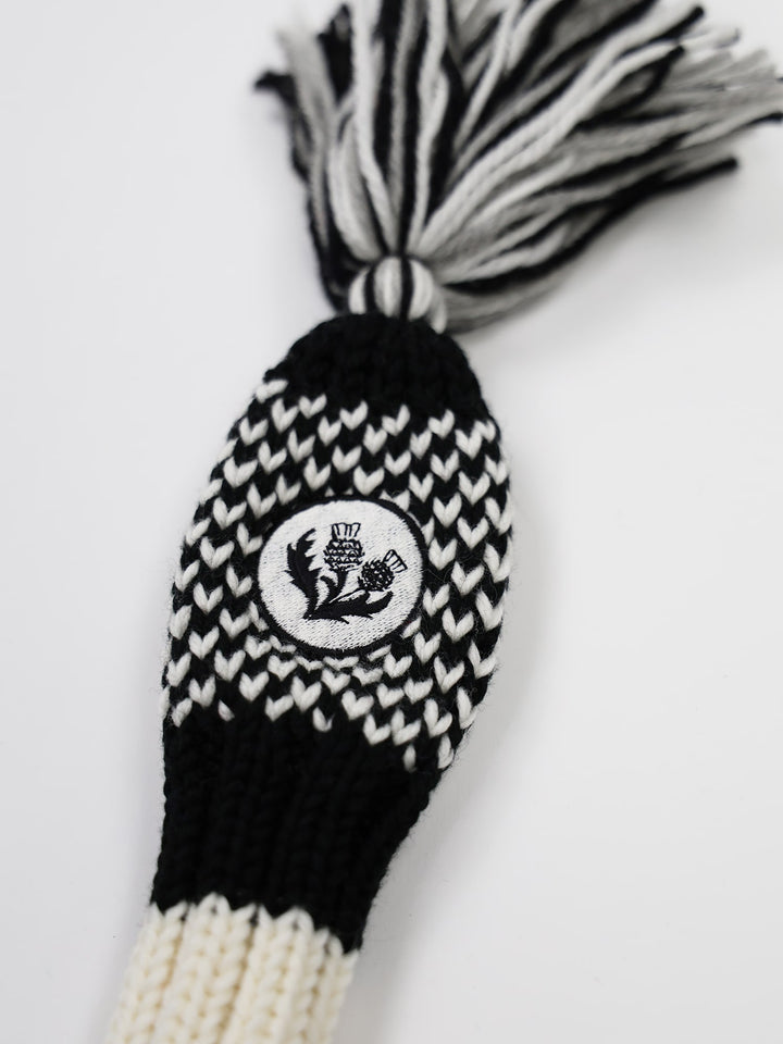 Knitted golf club cover in black and white with a thistle design patch