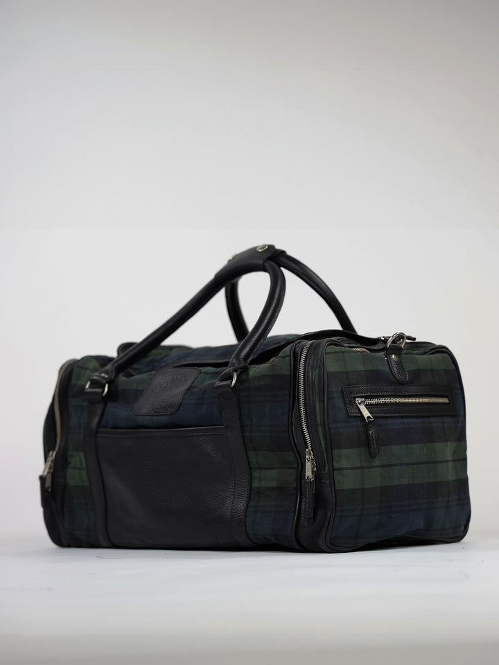 A stylish plaid duffel bag with black leather accents and multiple zippered compartments