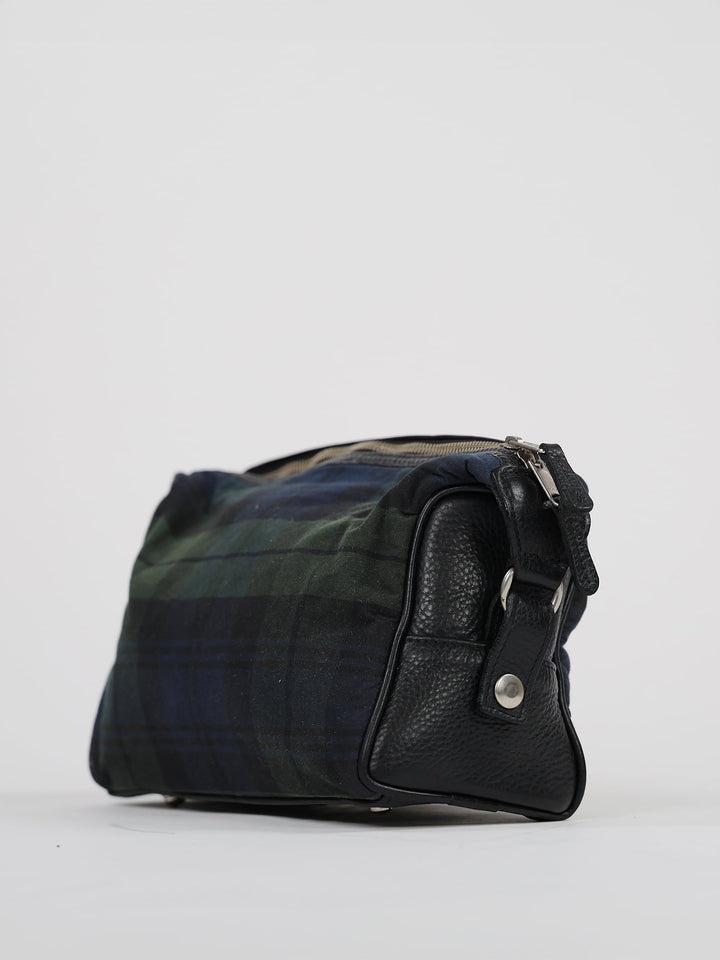 A plaid toiletry bag with black leather accents sits against a plain white background