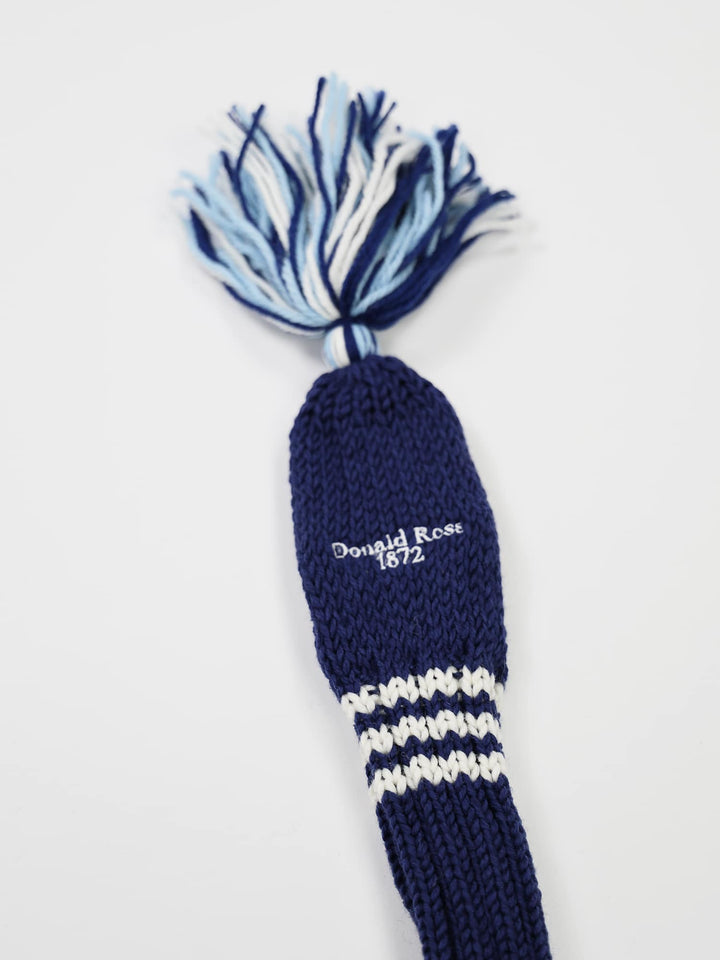 A navy blue knit golf club head cover with white stripes near the bottom and a top tassel in mixed blue hues