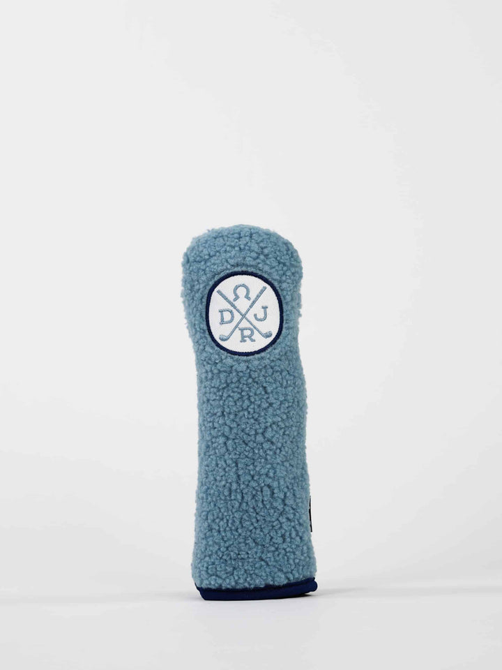 A soft, light blue textured golf club head cover stands upright against a white background
