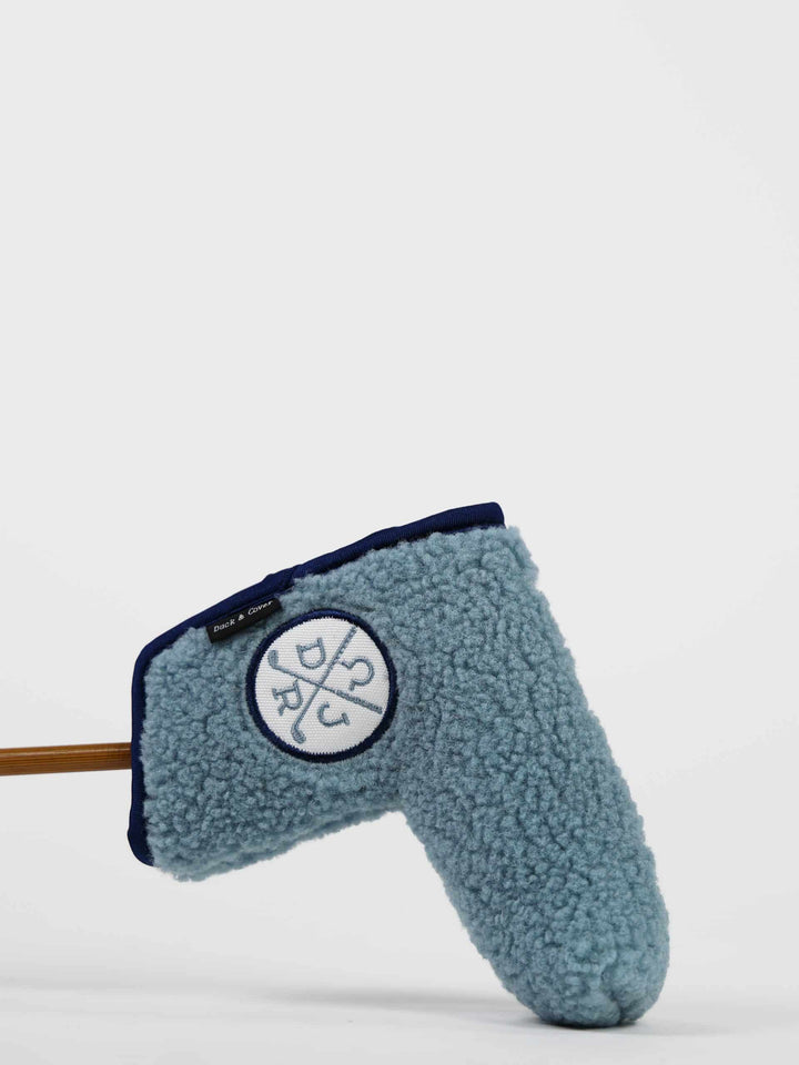 A blue fleece golf club head cover with a logo in a circular design is set against a plain white background