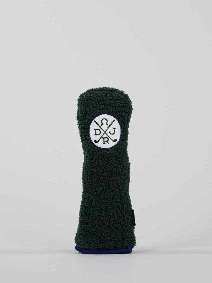 Dark green, textured golf club headcover with a circular logo featuring crossed lines and letters
