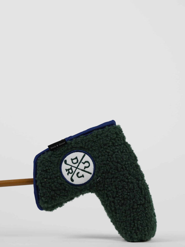 Close-up of a dark green, golf club head cover with a round white logo featuring crossed clubs