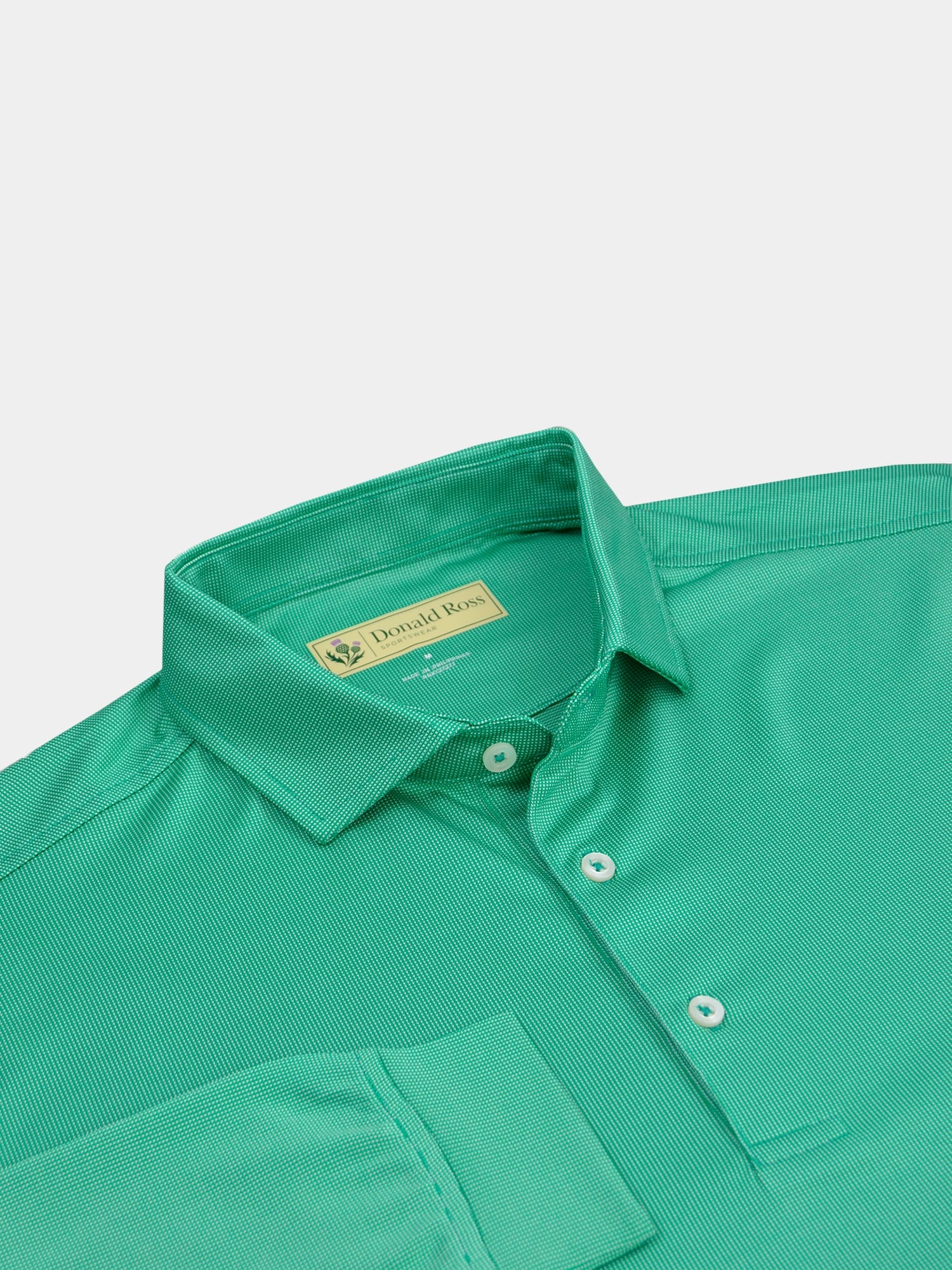 Green textured polo shirt with a structured collar and three white buttons. The sleeve of the shirt is laid over the front of the shirt