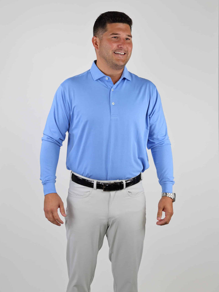 Man in bright sky blue long sleeve polo shirt and tan golf pants