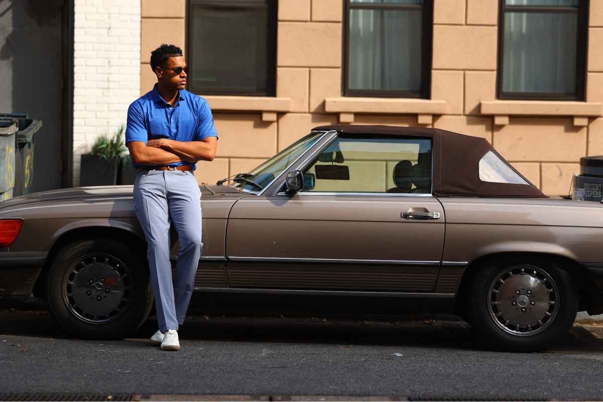 A man leaning against a car wearing Donald Ross Sportswear
