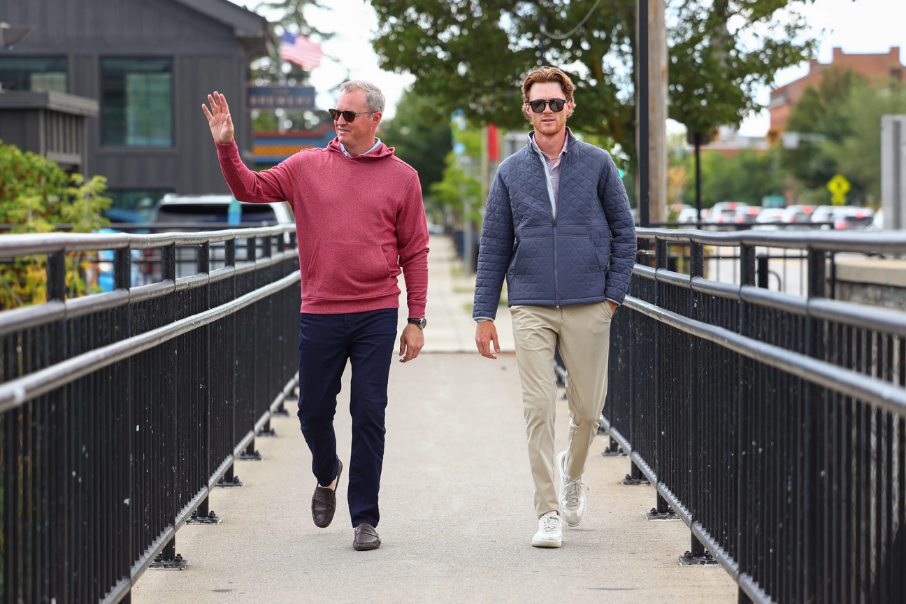 Men in golf wear walking across a bridge