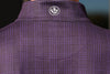 Close-up of a purple plaid shirt's back, featuring a white circular logo with a floral design centered at the base of the collar.