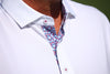 A man wearing a white polo shirt with a patterned red and blue floral print placket and white collar buttons.