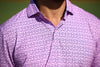 Man wearing a lavender polo shirt with a subtle geometric pattern against a green background.