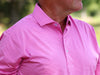 Man wearing a pink striped performance polo shirt outdoors.