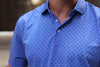 Man wearing a blue geometric patterned polo shirt with a button placket.