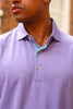 Man wearing a lavender polo shirt with a contrasting floral print placket and gold buttons.