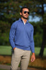 Man wearing a periwinkle blue quarter-zip pullover and khaki pants standing outdoors on a golf course.