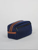 A navy blue toiletry bag with a brown zipper and a side strap is displayed at an angle against a light background.