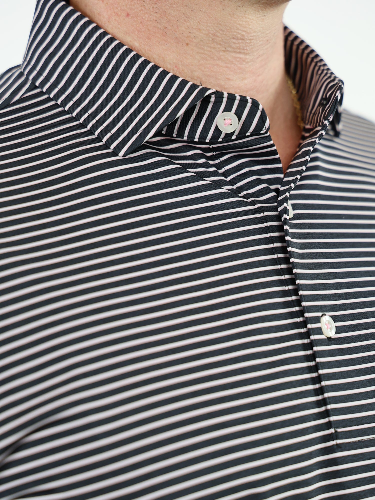 Close-up of a golfer wearing a black and white striped polo shirt with a button-down collar