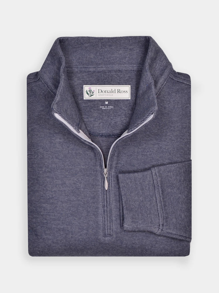Light gray golf quarter-zip sweater neatly folded on a light surface. The sweater features ribbed cuffs and a label at the collar, exuding a casual, elegant feel.
