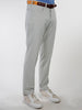 Man wearing light gray performance golf pants, brown belt, and beige sneakers, standing against a plain white background