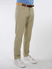 A person wearing beige performance golf pants with a brown belt, blue-striped shirt, and white sneakers stands against a plain white background.