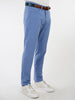 Man wearing light blue performance golf pants with a brown belt, polo shirt, and white sneakers