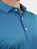 Close-up of a man wearing a vibrant blue button-up shirt with a small green geo print pattern
