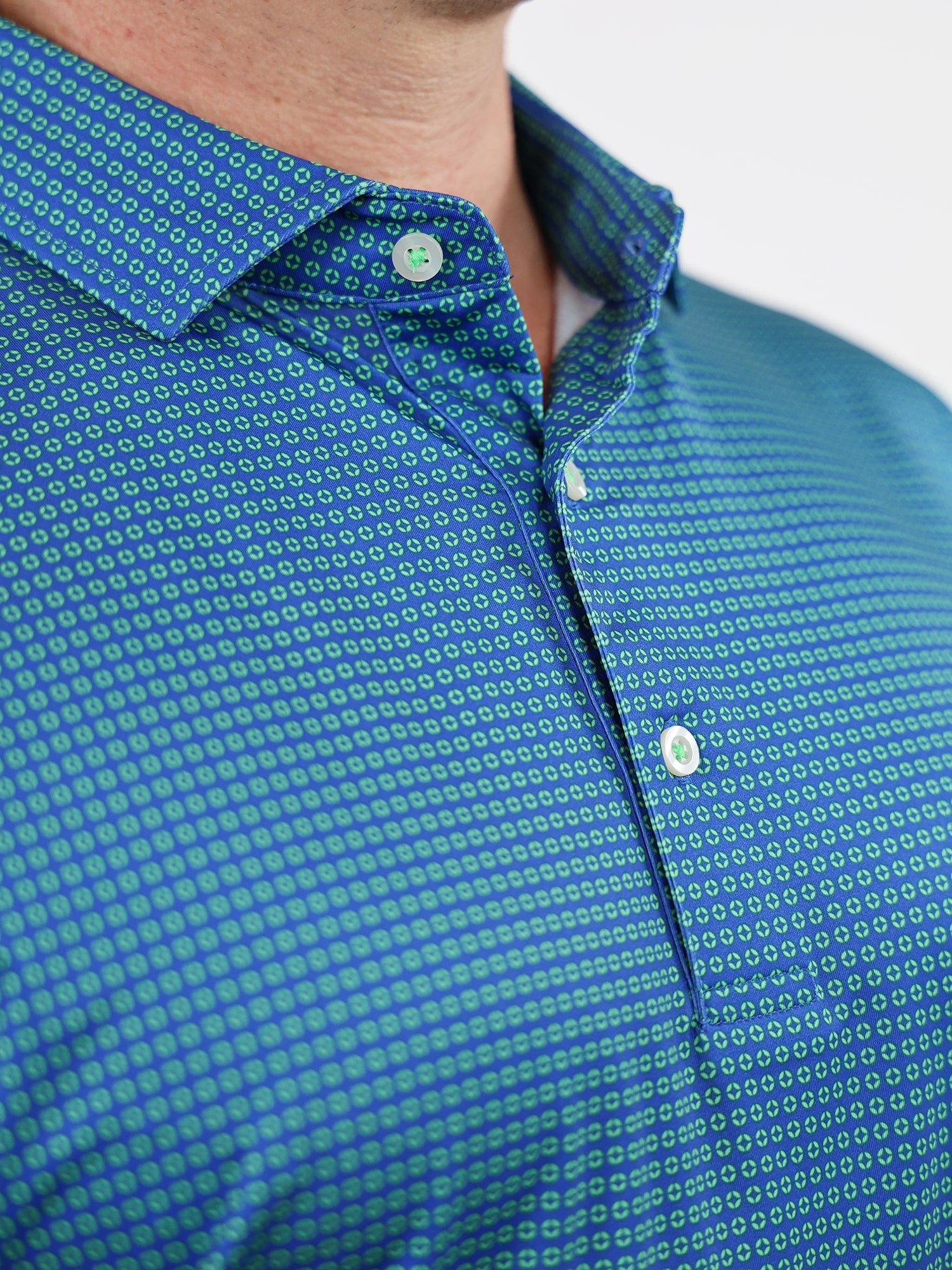 Close-up of a man wearing a vibrant blue button-up shirt with a small green geo print pattern