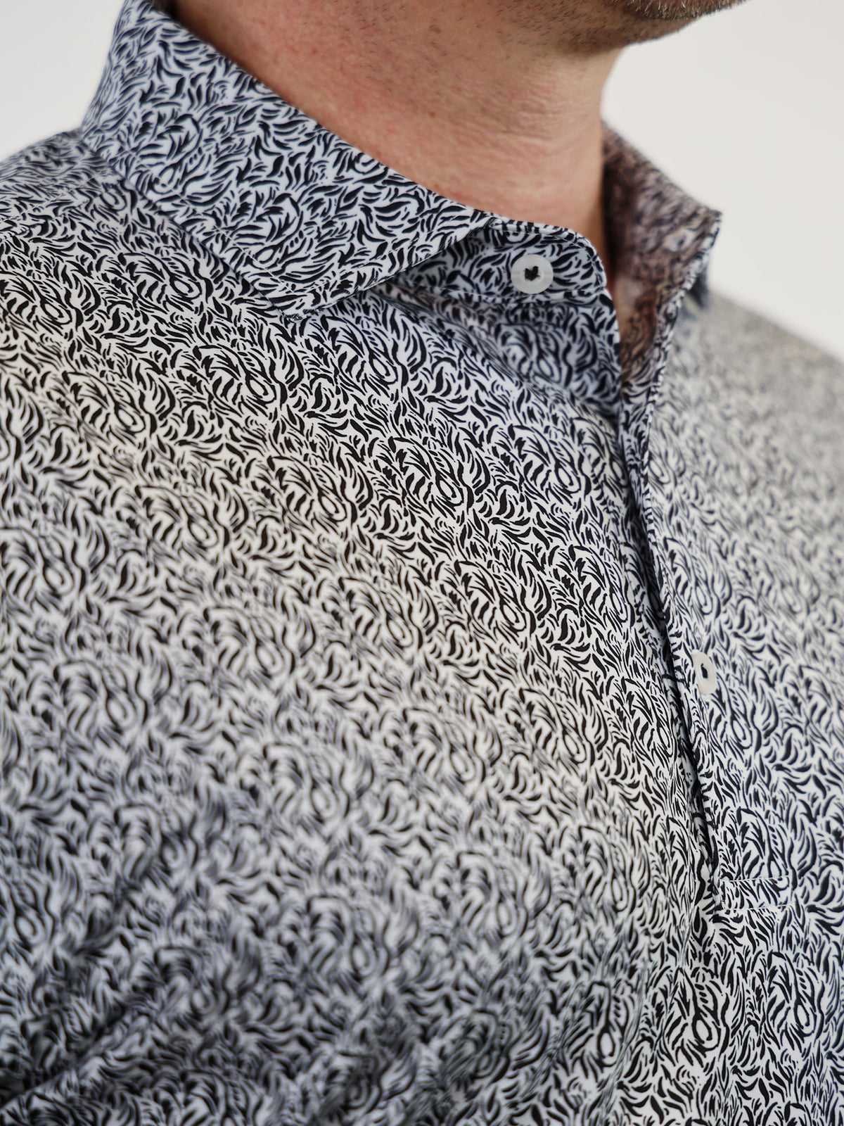 Close-up of a person wearing a black and white flame patterned shirt with intricate swirl designs. The look is stylish and sophisticated.