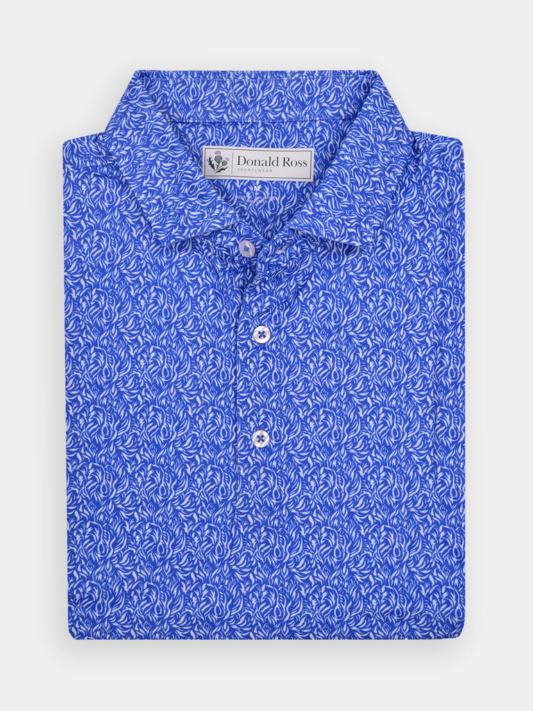 Folded blue golf polo shirt with intricate white flame pattern and three buttons