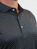 Close-up of a person wearing a black shirt with a small white pepper pattern. The shirt is buttoned, conveying a neat and casual look.