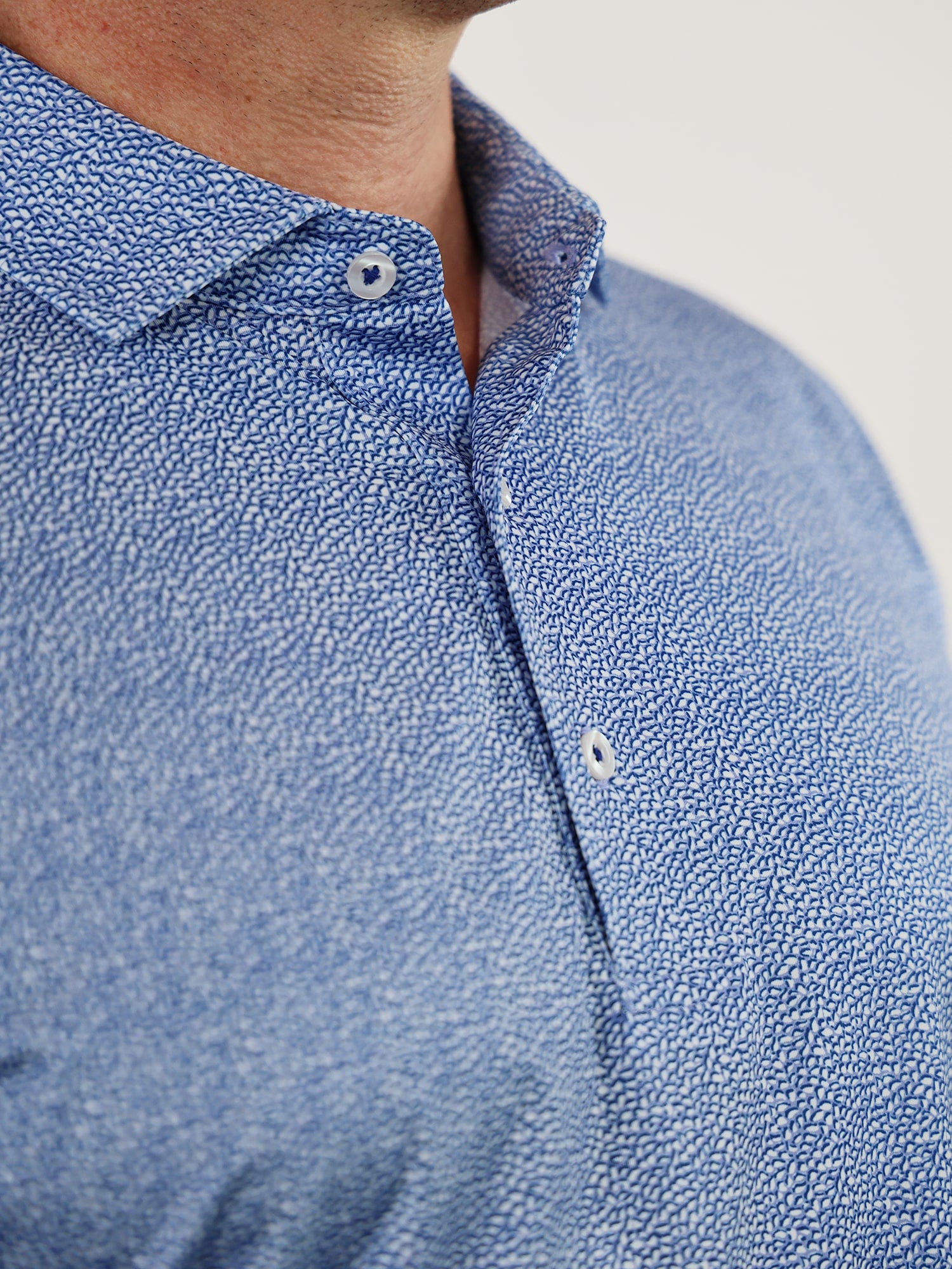 Close-up of a blue button-up shirt with a detailed w]]water drop pattern, featuring a collar and part of the shoulder, creating a casual yet stylish look