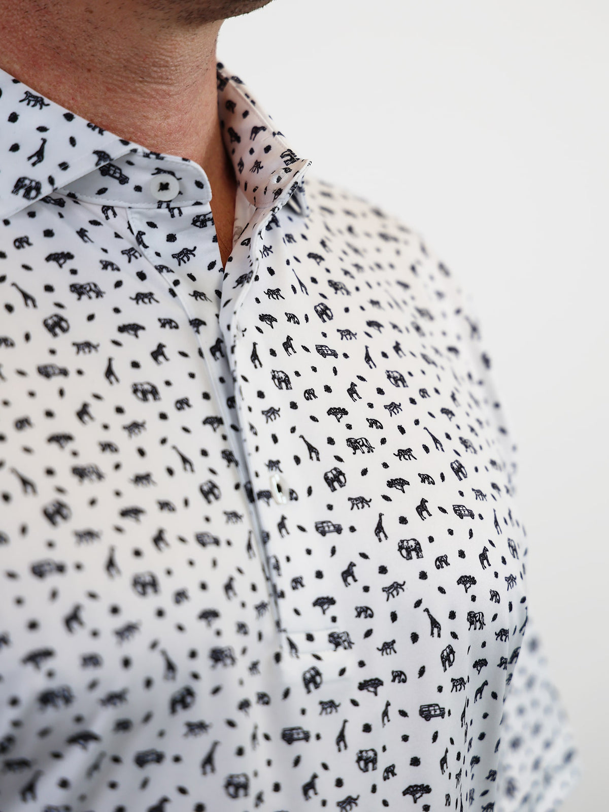 Close-up of a person wearing a white shirt with a playful black safari animal pattern, featuring elephants and giraffes