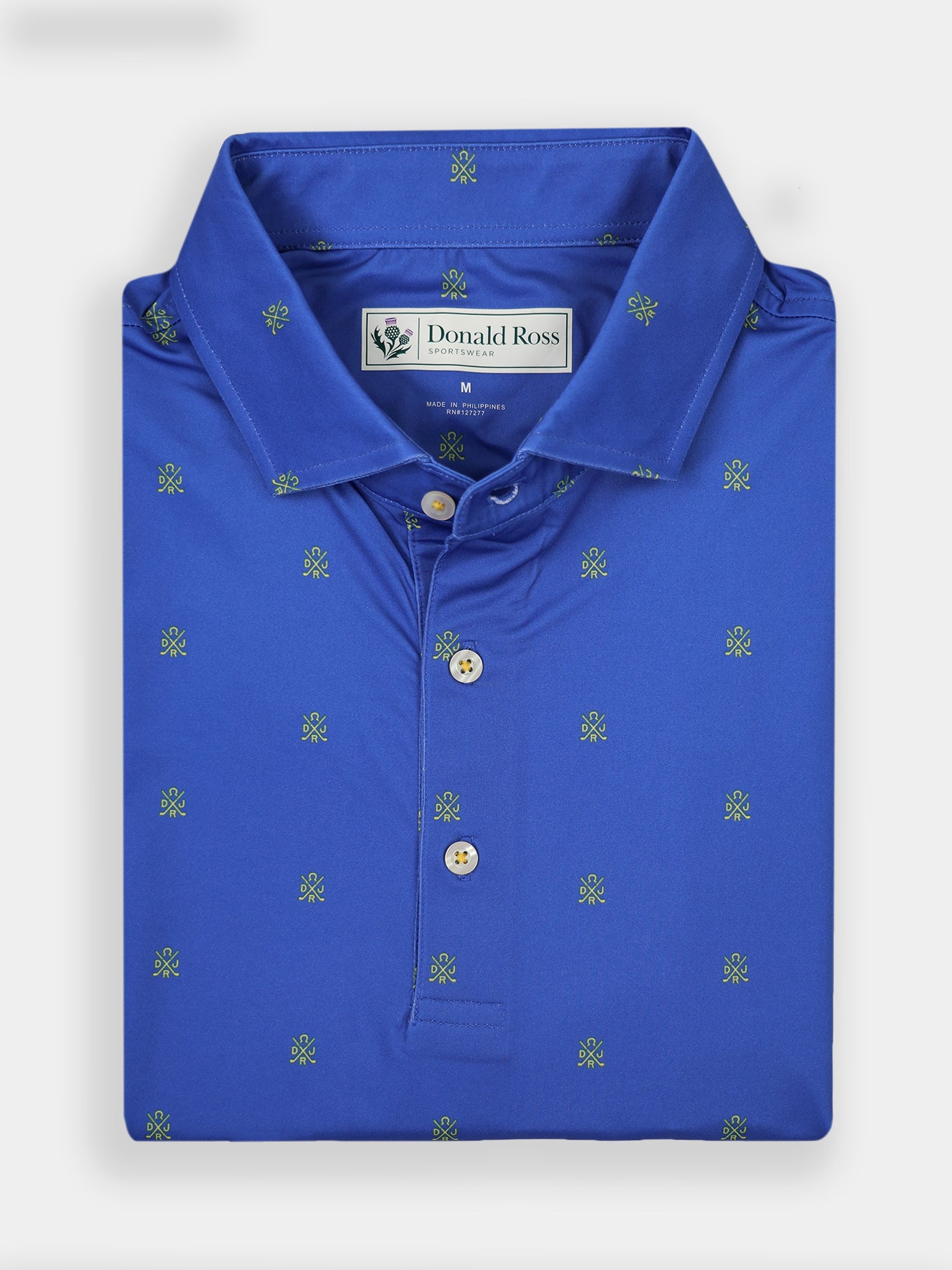 Folded blue polo shirt with small green embroidered patterns, featuring a neat collar and three buttons