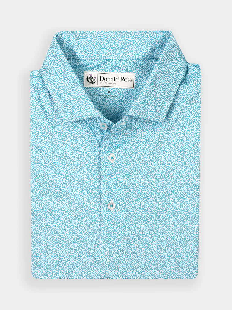 Light blue polo shirt with an intricate white vine attern, neatly folded. Features a collar, buttons, and a label on the inside. Crisp, elegant design.