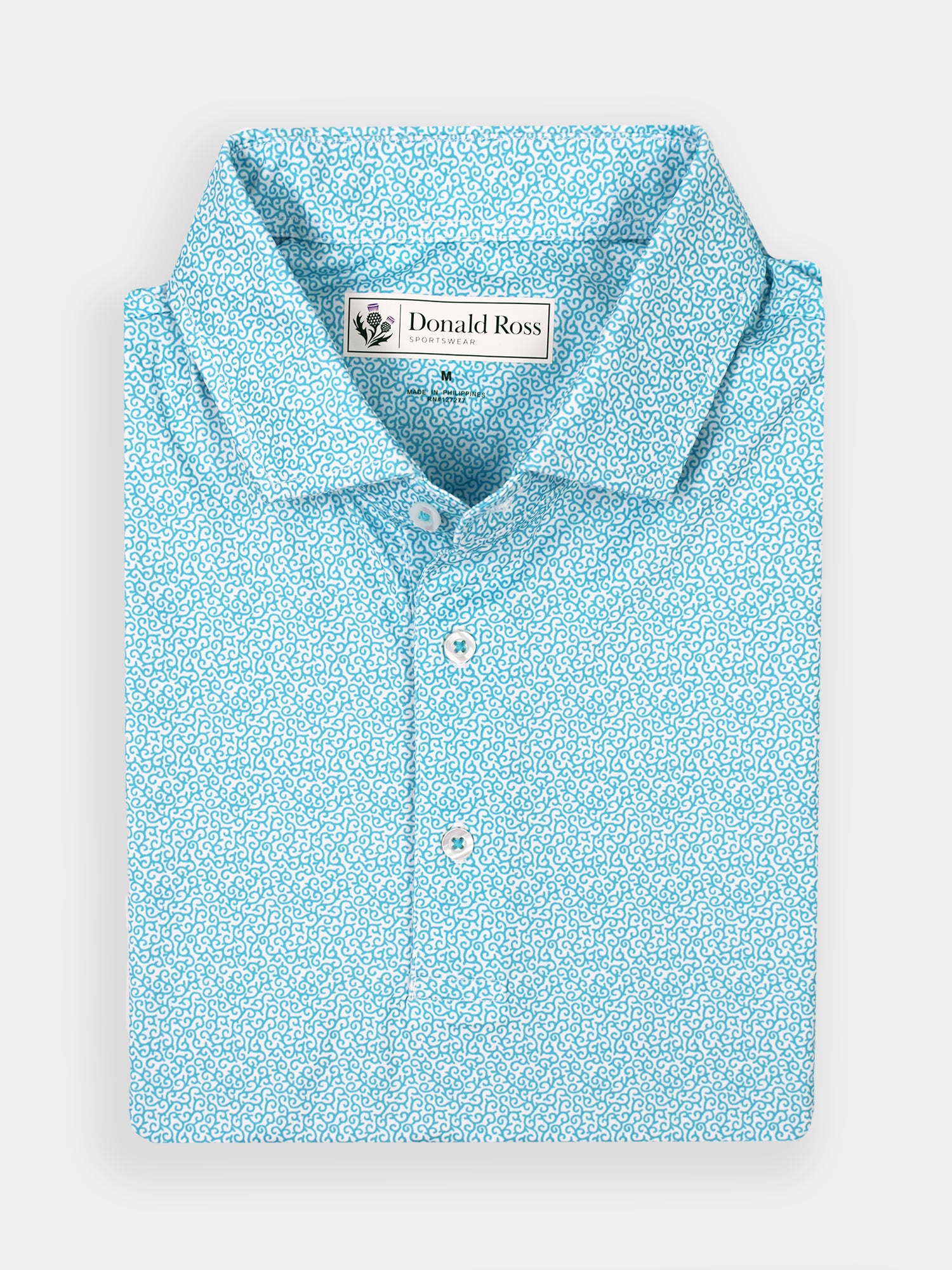 Light blue polo shirt with an intricate white vine attern, neatly folded. Features a collar, buttons, and a label on the inside. Crisp, elegant design.