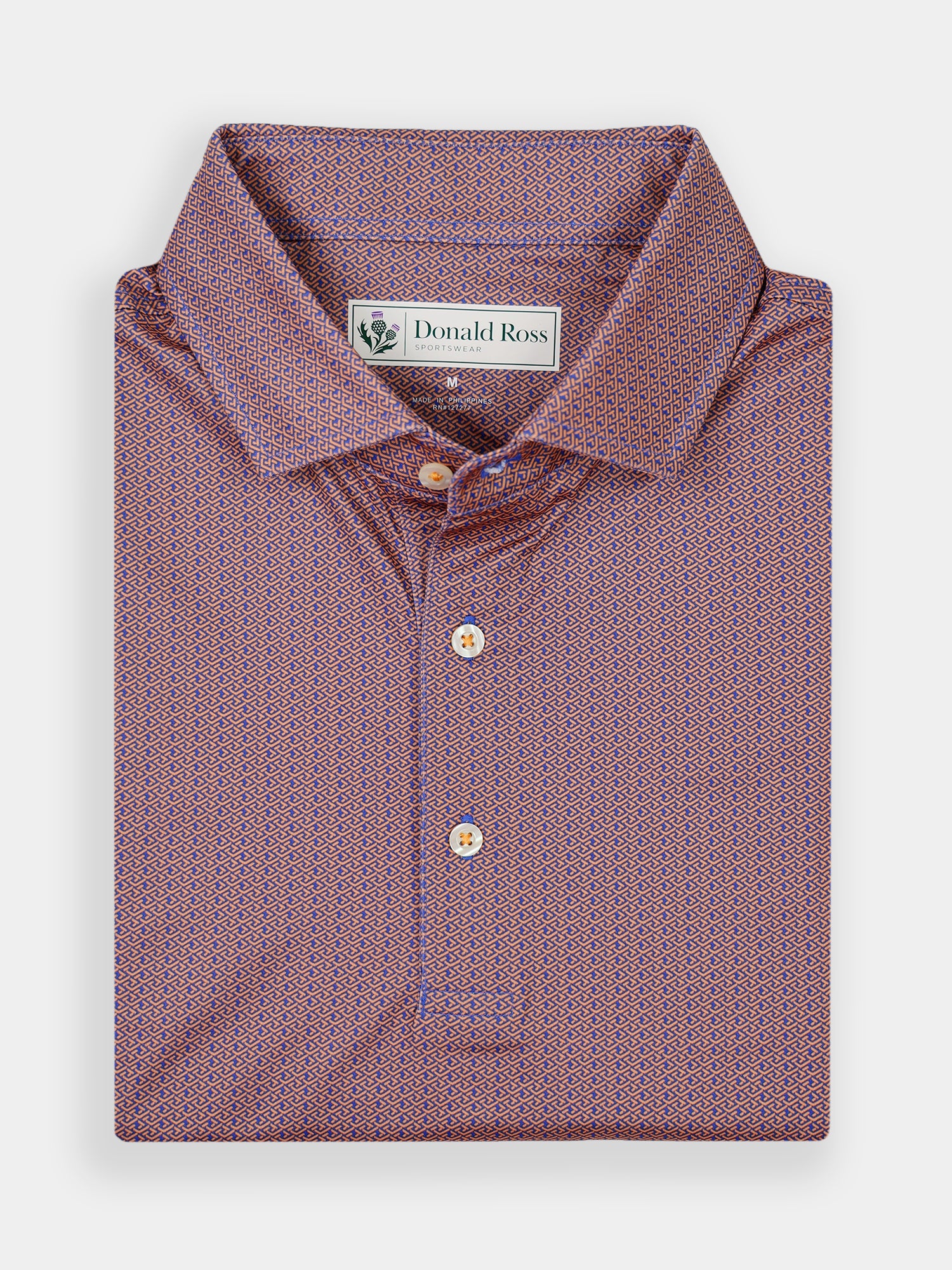 Folded polo shirt in a detailed pattern of small interlocking geometric shapes in a mix of red and blue hues