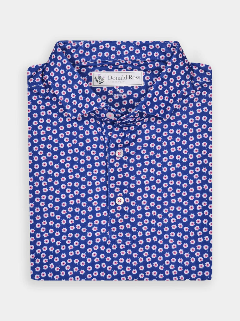 Folded blue floral-patterned polo shirt with pink and white flowers, neatly arranged on a white background