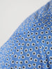 Close-up of the sleeve of a blue golf polo with a pattern of small white and black flowers, creating a playful and vibrant texture.