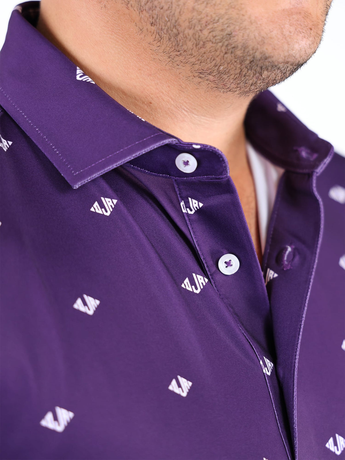 Close-up of a person wearing a purple collared shirt with subtle white Donald Ross logos. The focus is on the collar and button details.