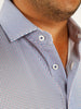 Close-up of a man wearing a patterned button-up shirt with small blue and red geometric designs