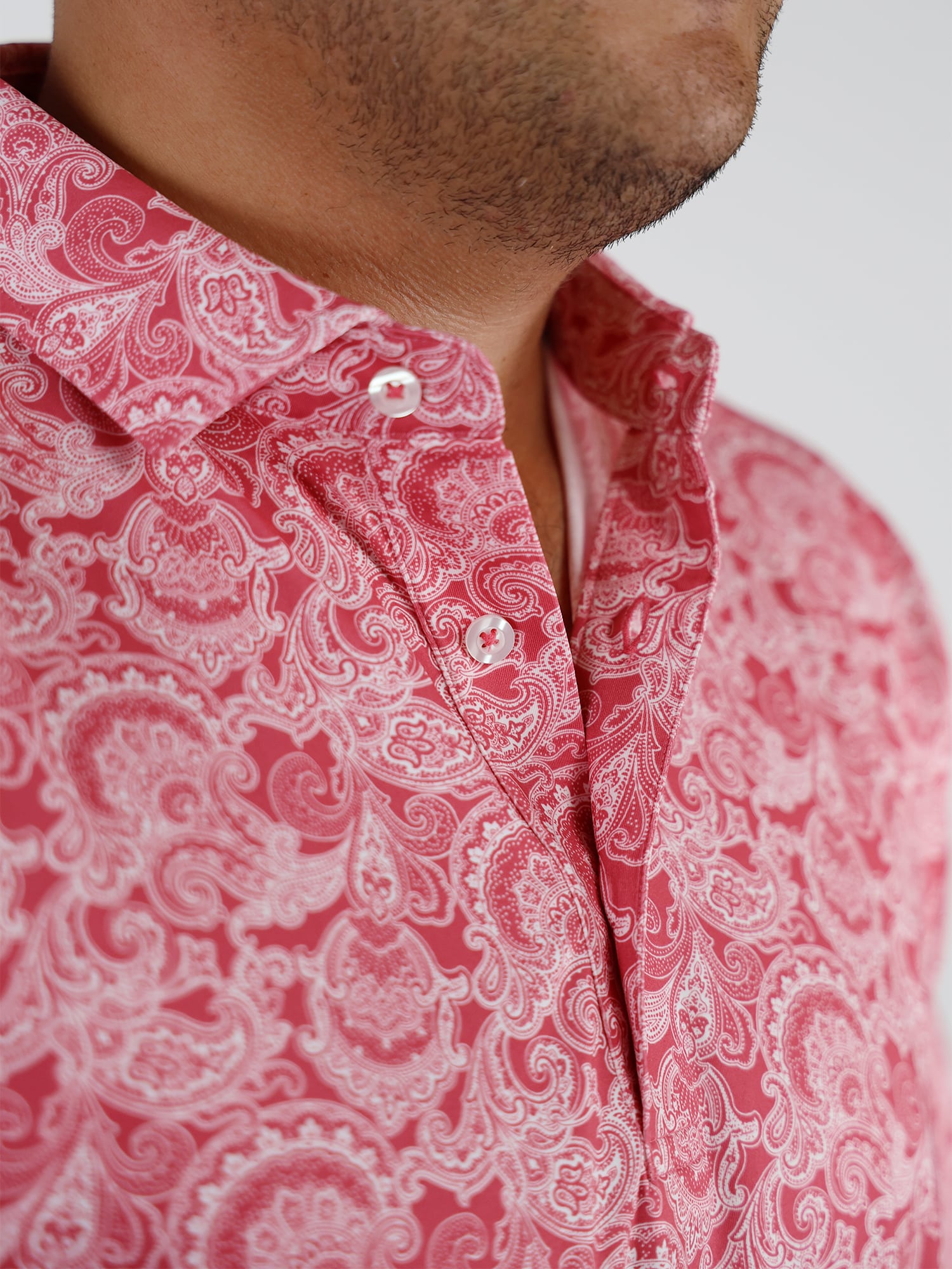 Close-up of a person wearing a red paisley-patterned shirt, showcasing intricate white designs.