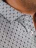 Close-up of a light blue shirt with a small black Donald Ross print pattern. The shirt has silver buttons and a neatly folded collar, conveying a polished look.
