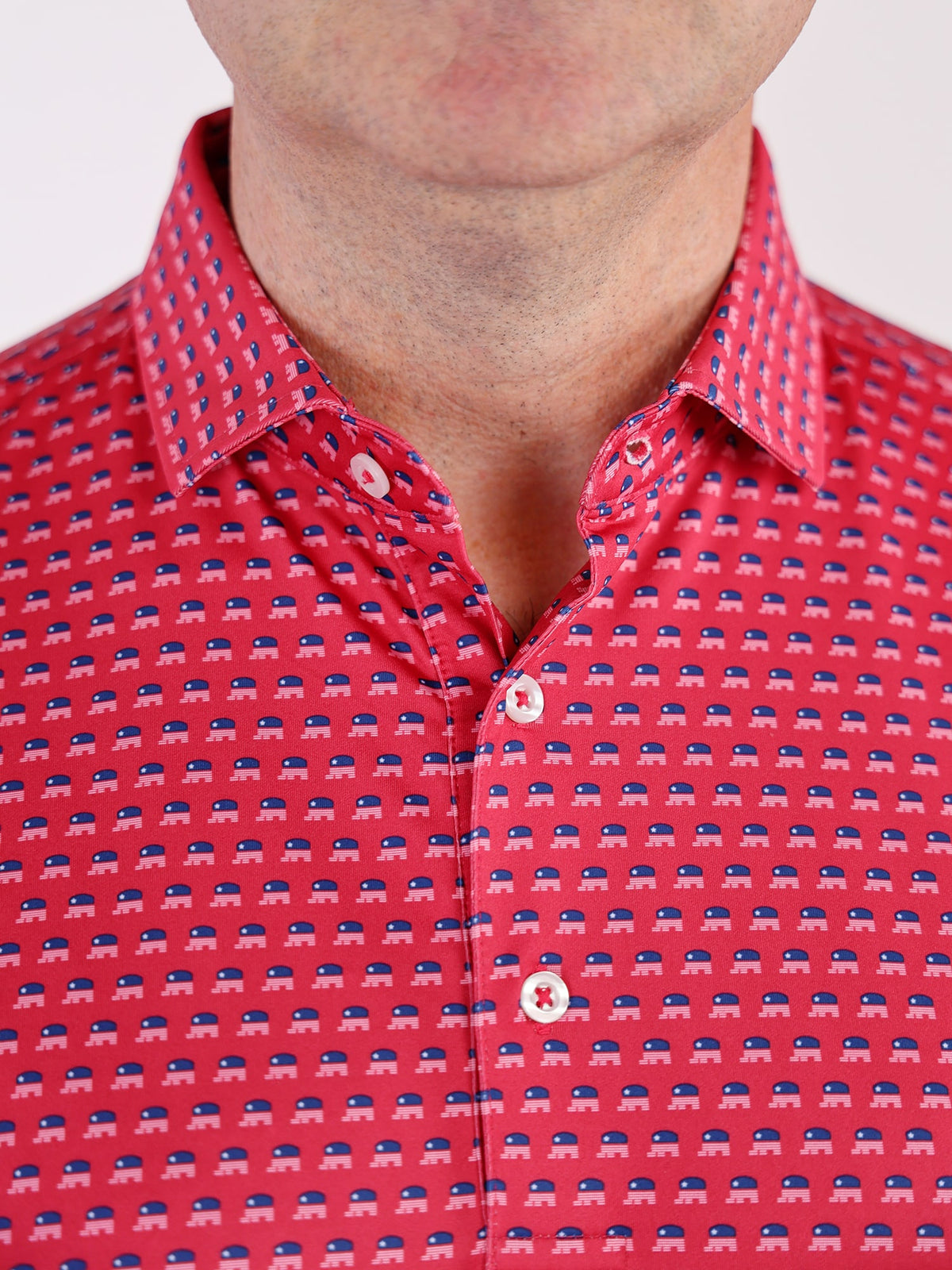 Close-up of a man's upper chest wearing a red shirt with small blue and white elephant patterns, buttoned up with white buttons, conveying a playful tone.