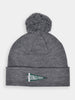 Gray knit beanie with a large pom-pom on top. Features a folded brim with a green pennant logo displaying "Donald Ross" in white letters.