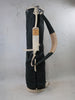 Black and cream canvas golf bag with leather accents and shoulder strap displayed against a concrete backdrop.