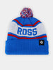 Blue and white knit beanie with "ROSS" in bold letters. Features red stripes, a multicolored pom-pom, and a black logo patch, conveying a sporty vibe.