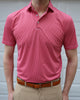 A person is wearing a red patterned polo shirt and beige pants, standing in front of a white garage door.