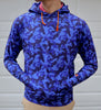 A person is standing with their hands in the pockets of a blue camouflage hoodie.