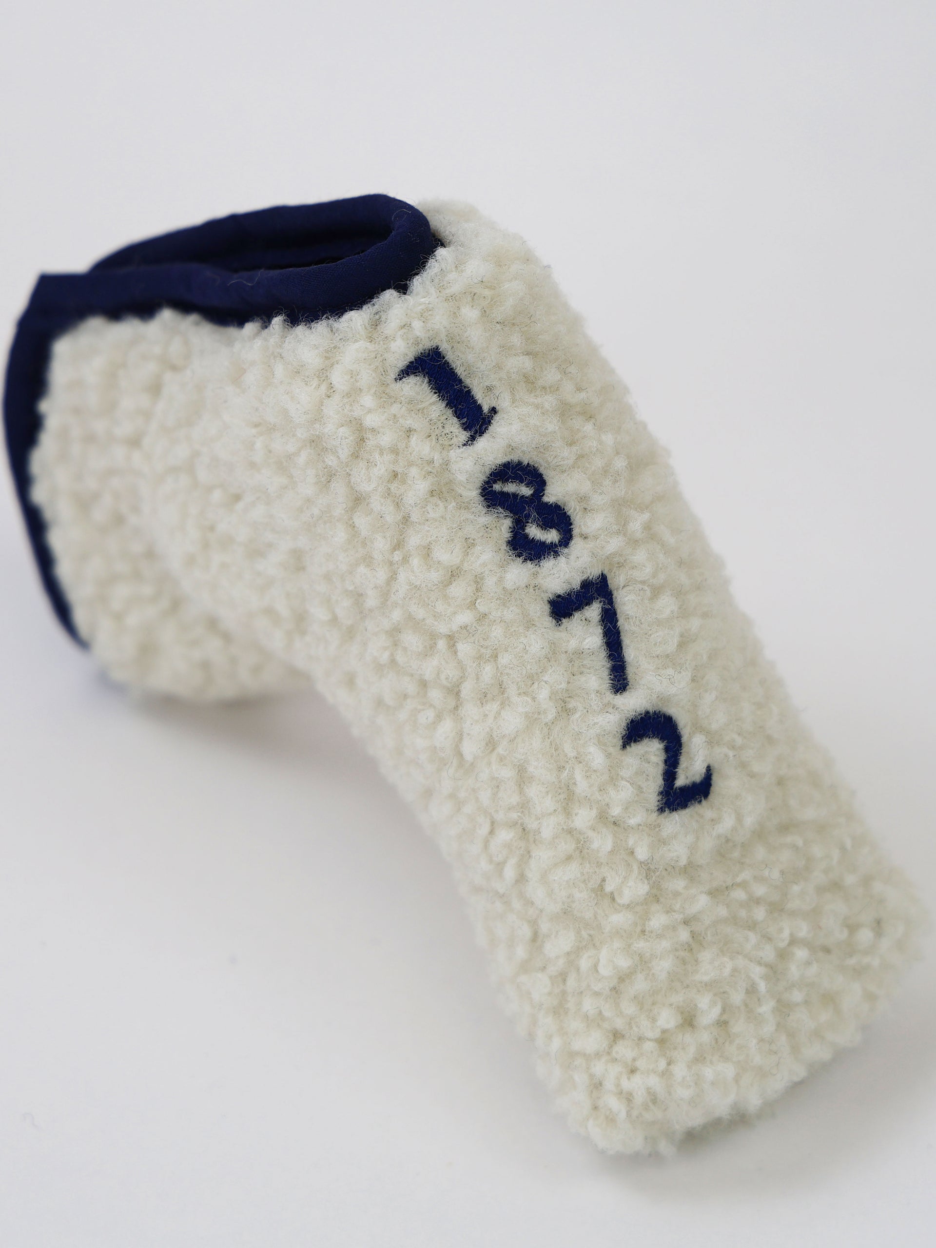 Cream-colored knit headcover with navy trim and embroidered "1812" designation displayed against a white background.